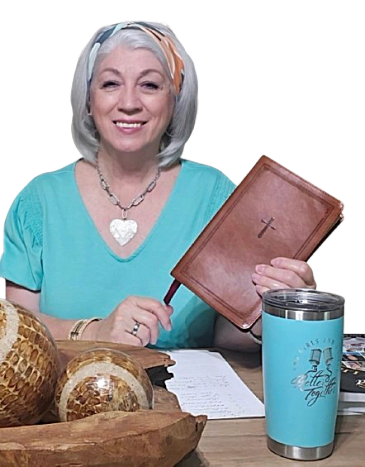 Smiling woman holding a Bible at a wooden table.