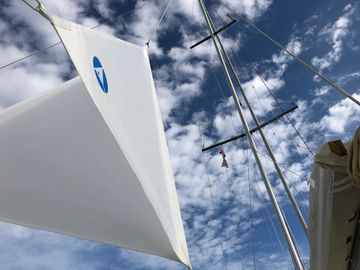 A sailboat with an anchor riding sail - double sided delta shaped. Sail against blue sky. Mast.