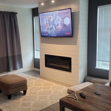 Modern living room with a mounted TV and fireplace.