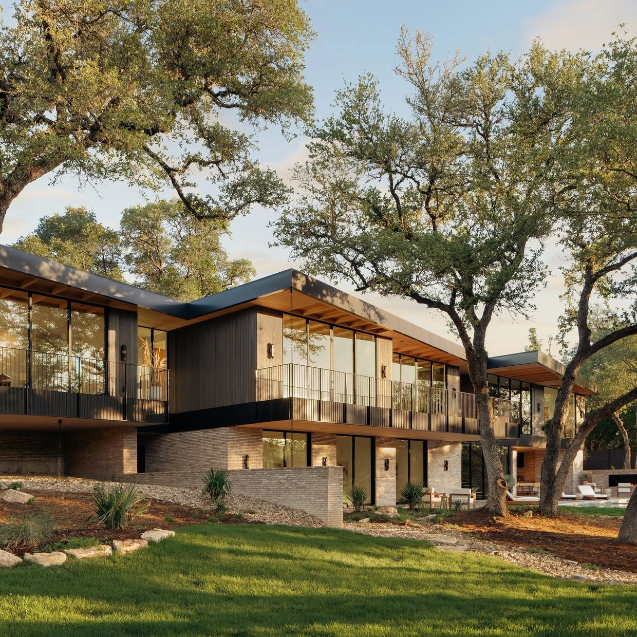 Modern two-story house with large windows and surrounding trees.