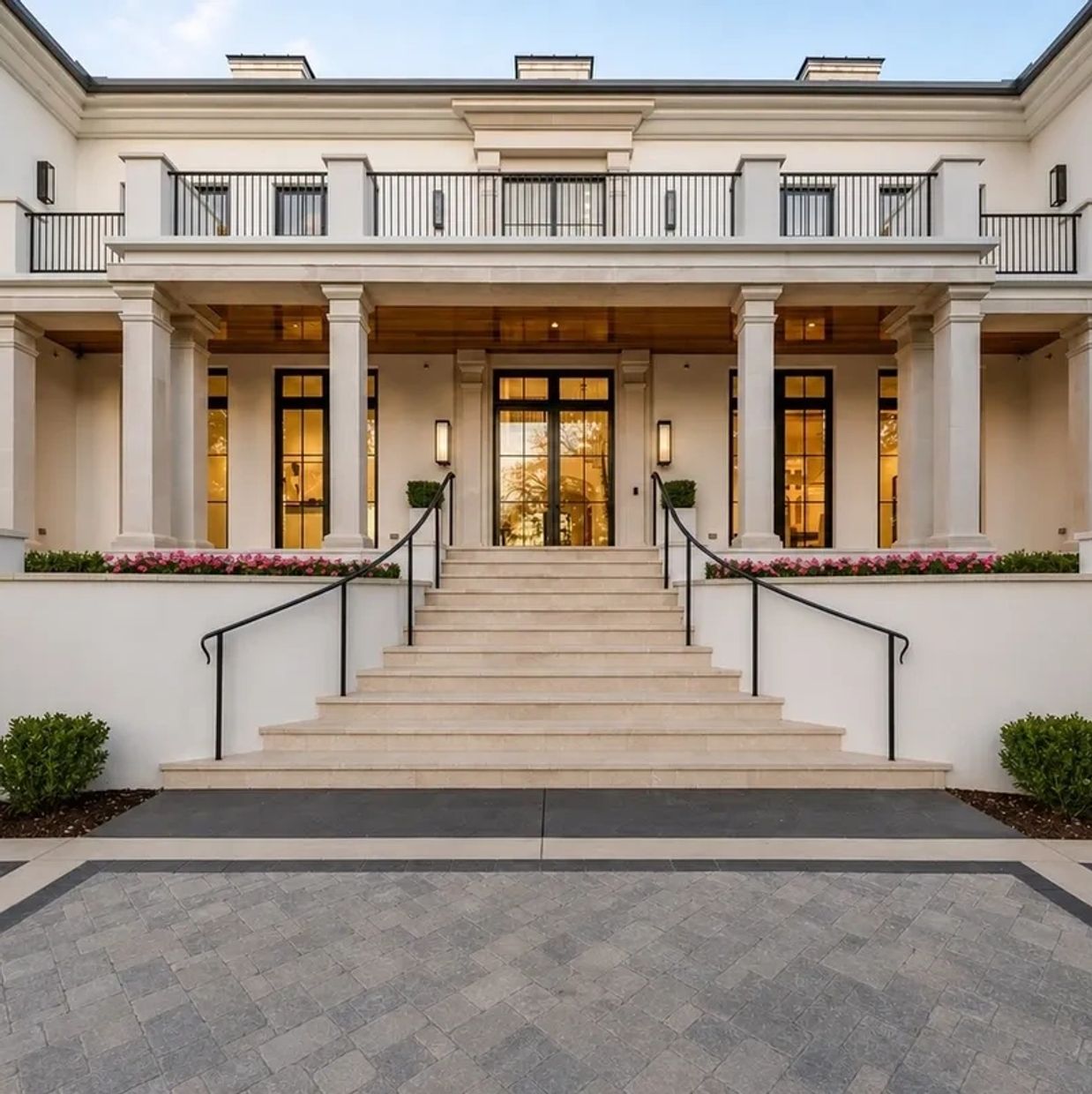 Elegant mansion entrance with grand staircase and tall pillars.