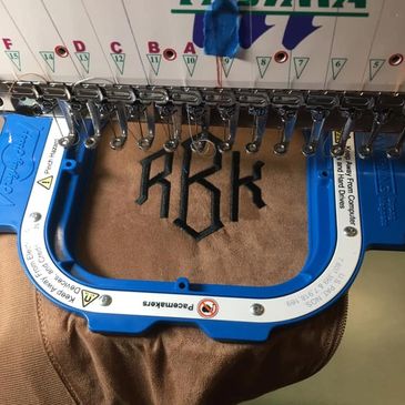 Shirt being embroidered with black thread with machine in Edinboro, PA