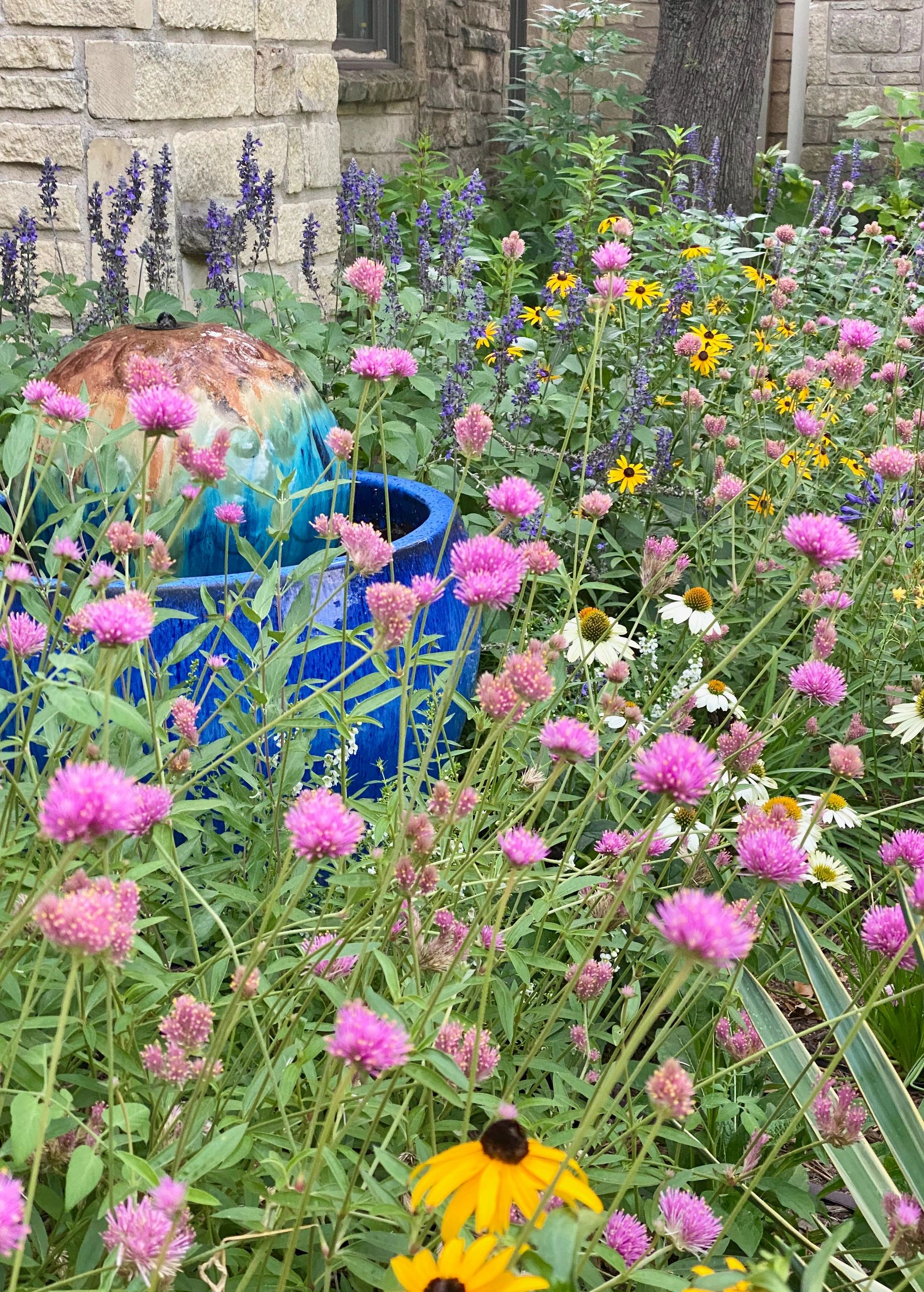 garden with blue fountain yellow flowers and pink flowers