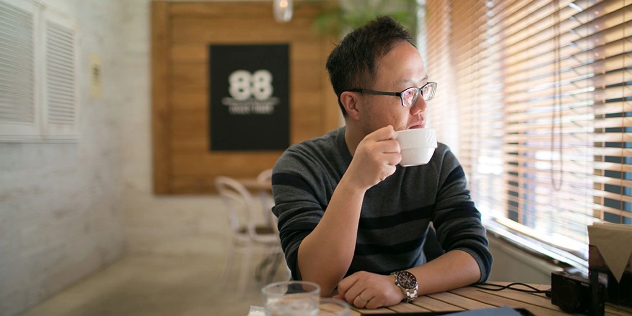 Man drinking coffee by the window in a cafe.