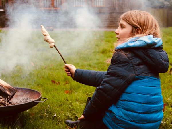 Photo of child making bread over the fire