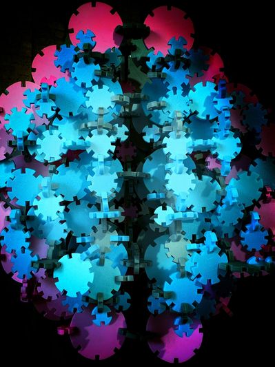 Colorful interconnected plastic gears illuminated in blue and pink.