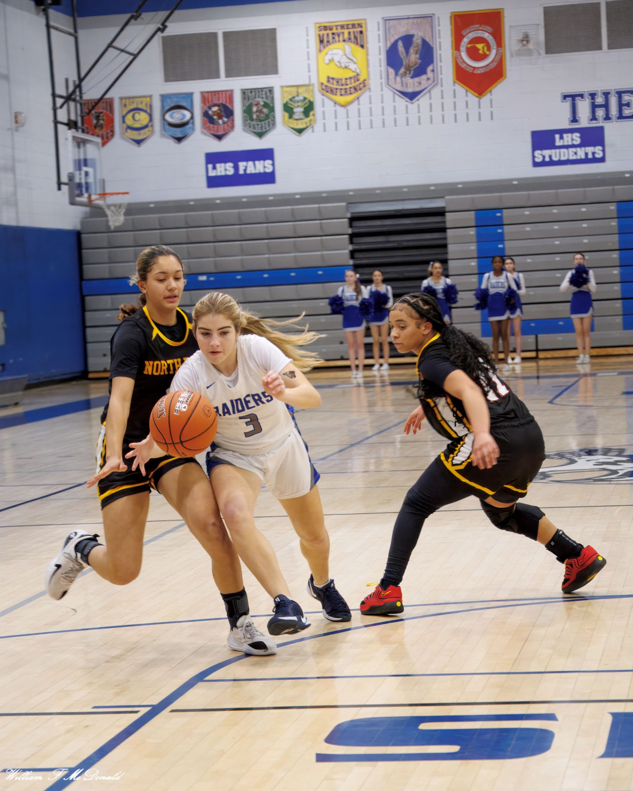 High school girls basketball game with players competing intensely on the court.