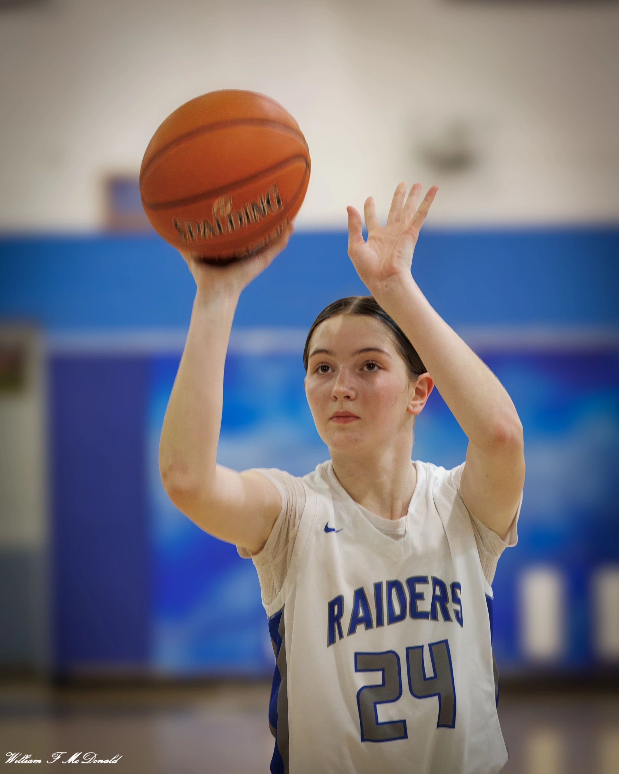 Young basketball player shoots a free throw in a gym.