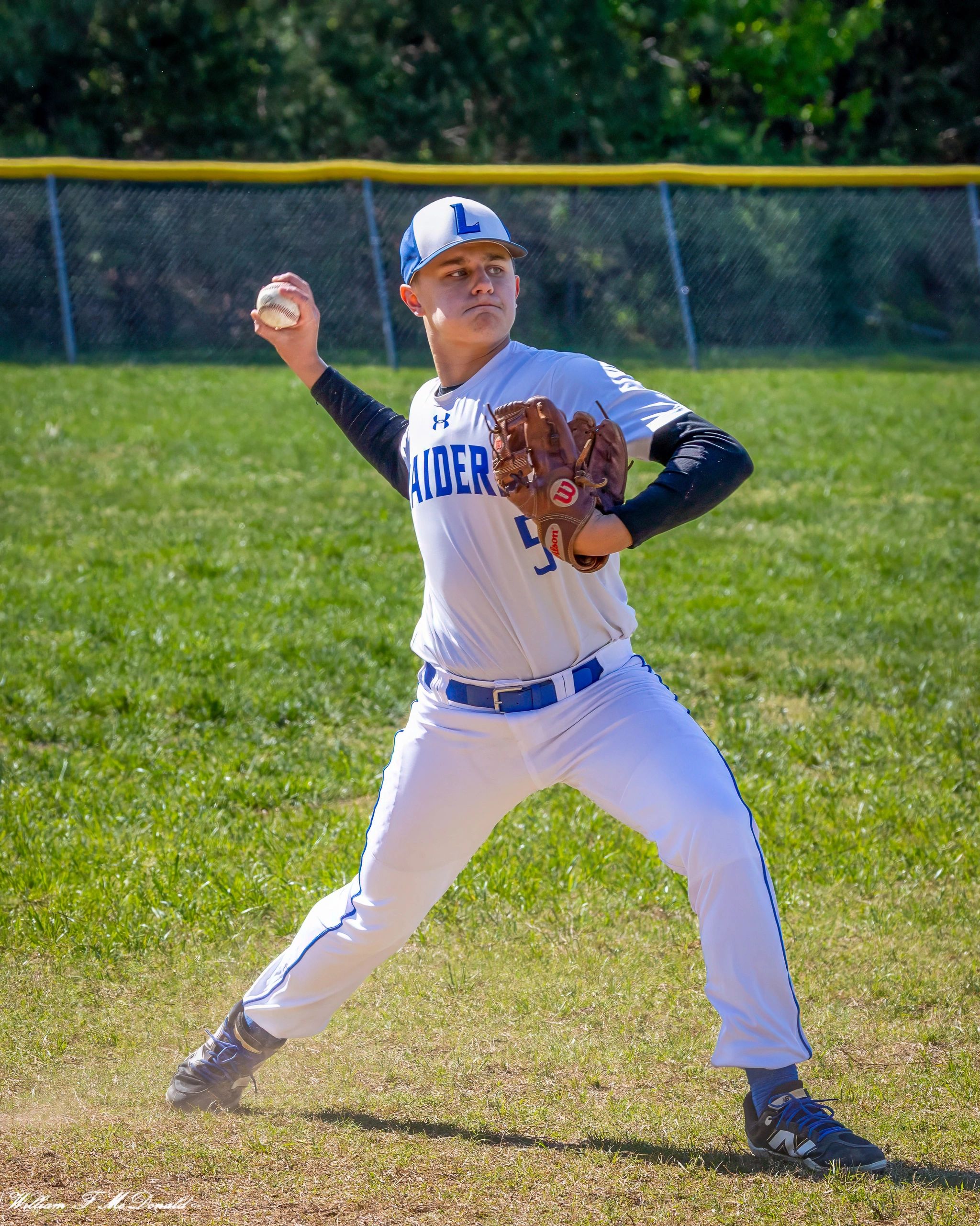 Baseball player preparing to pitch on a sunny field.