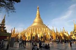 Golden pagoda with visitors at its base under a clear sky.