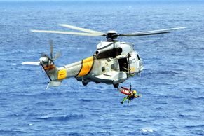Rescue operation with a helicopter over the ocean.