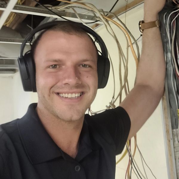 Daniel Coleman smiling while working on electrical panel wiring