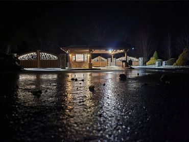 Driveway and gate illuminated by custom landscape and security lighting at night