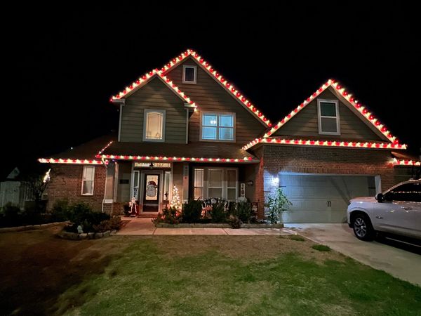 House decorated with red and white Christmas lights at night.