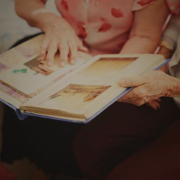 An elderly person looking through a photo album filled with old pictures.