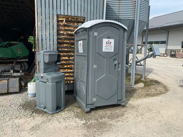 Portable toilet on a farm with portable handwash sink.