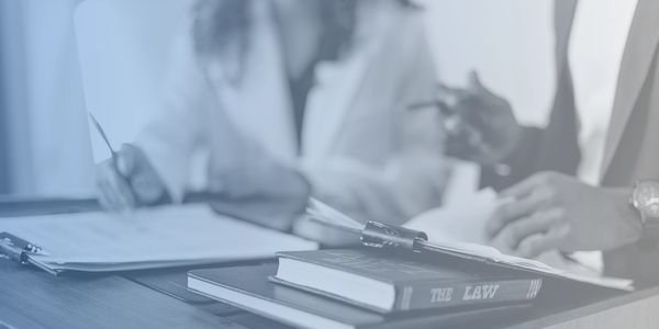 Law books and legal documents on a desk with professionals discussing.