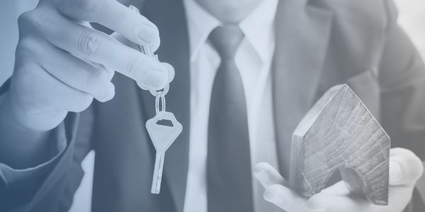 Real estate agent holding a house model and key.