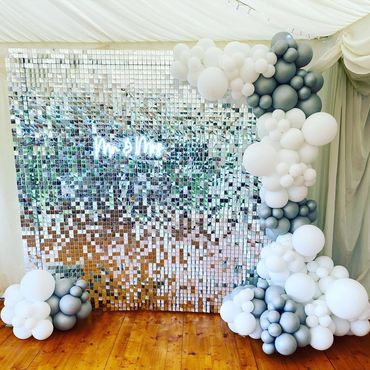 Silver sequin wall with white and silver balloons with mr & mrs neon sign