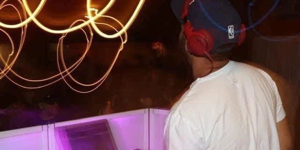 DJ wearing red headphones performing with light trails in the background.