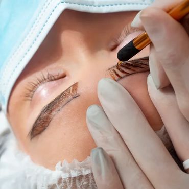 Close-up of a permanent makeup artist applying pigment to an eyebrow.