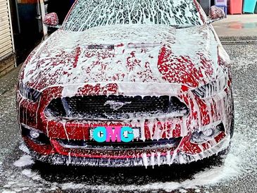 Red Mustang covered in soap during a car wash.