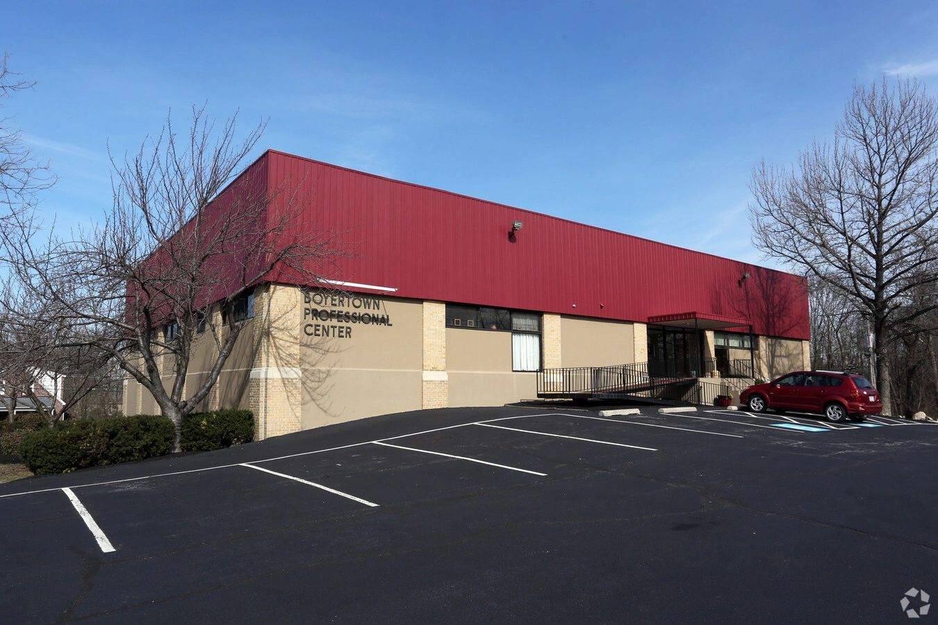 A professional center building with a red upper facade and empty parking spaces.