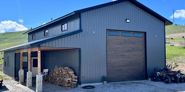Modern metal barn with wood accents in a rural setting.