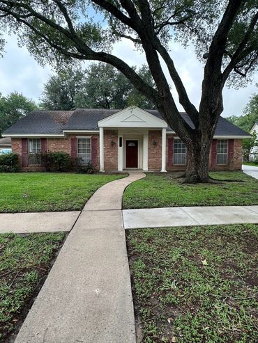 The finished walkway and sidewalk of a house with an oak tree.