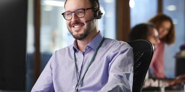 Smiling customer support agent wearing headset in an office.