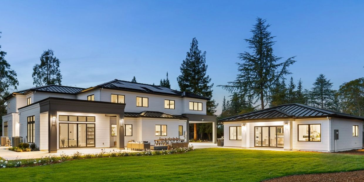 Modern large house with a lawn at dusk.