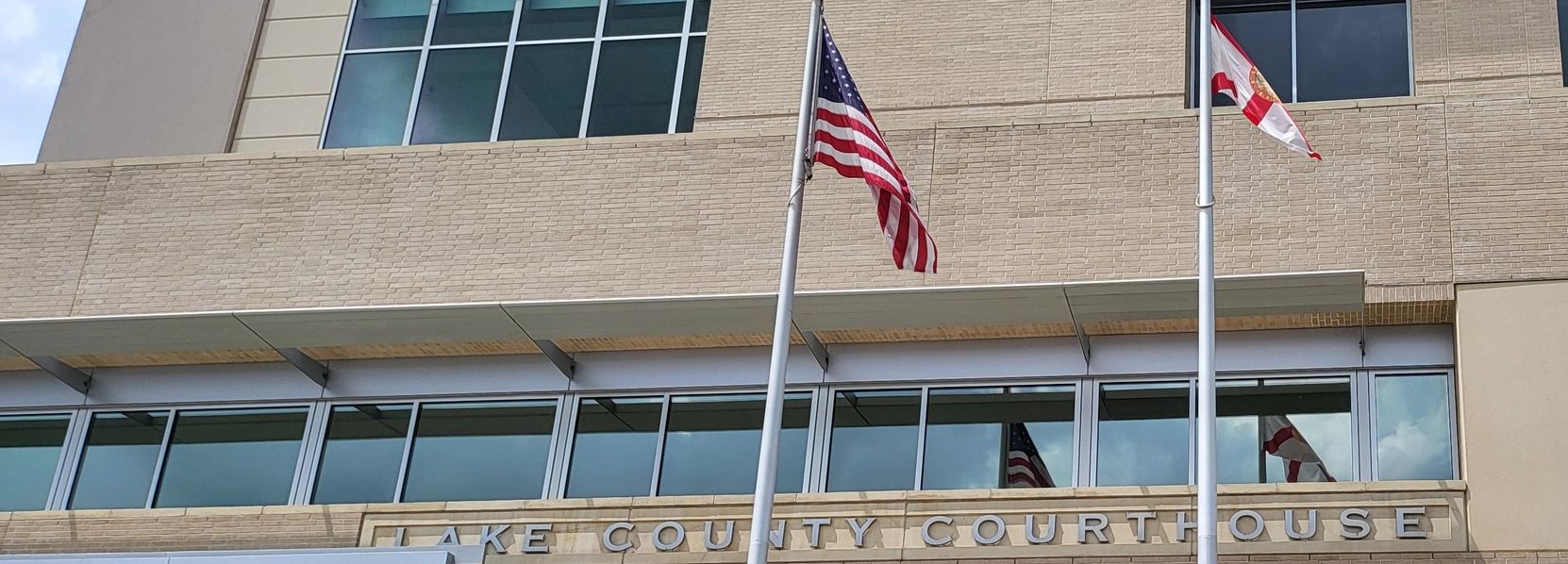 Picture of the american flag and the Florida State Flag in front of the Lake County Court House