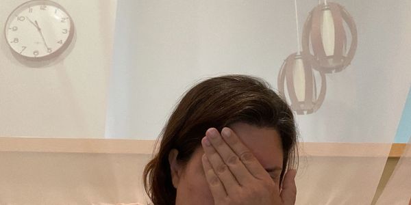 Person covering face with hand indoors.