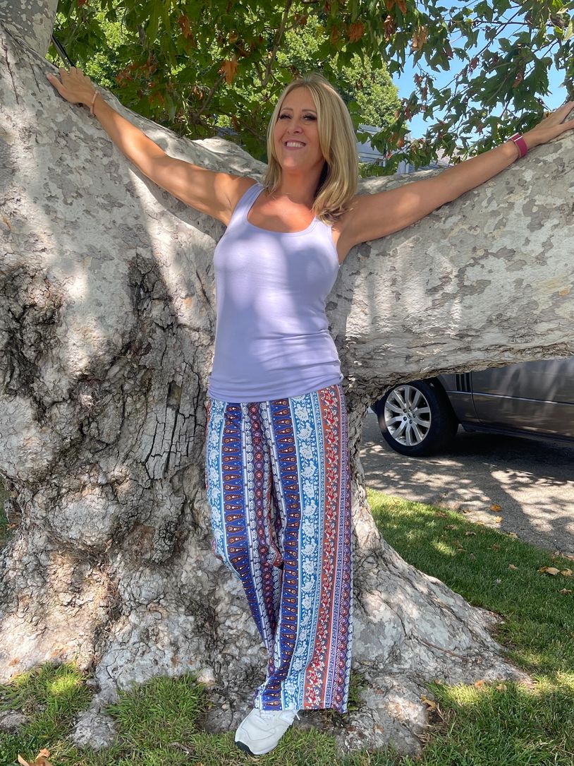 Woman posing with arms outstretched on a large tree.