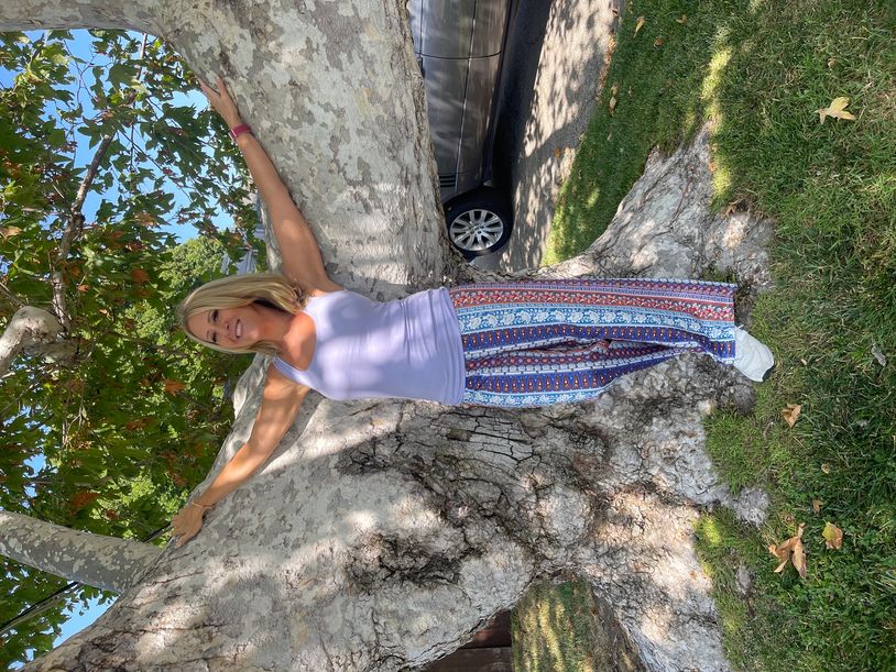 Woman posing with arms outstretched on a large tree.