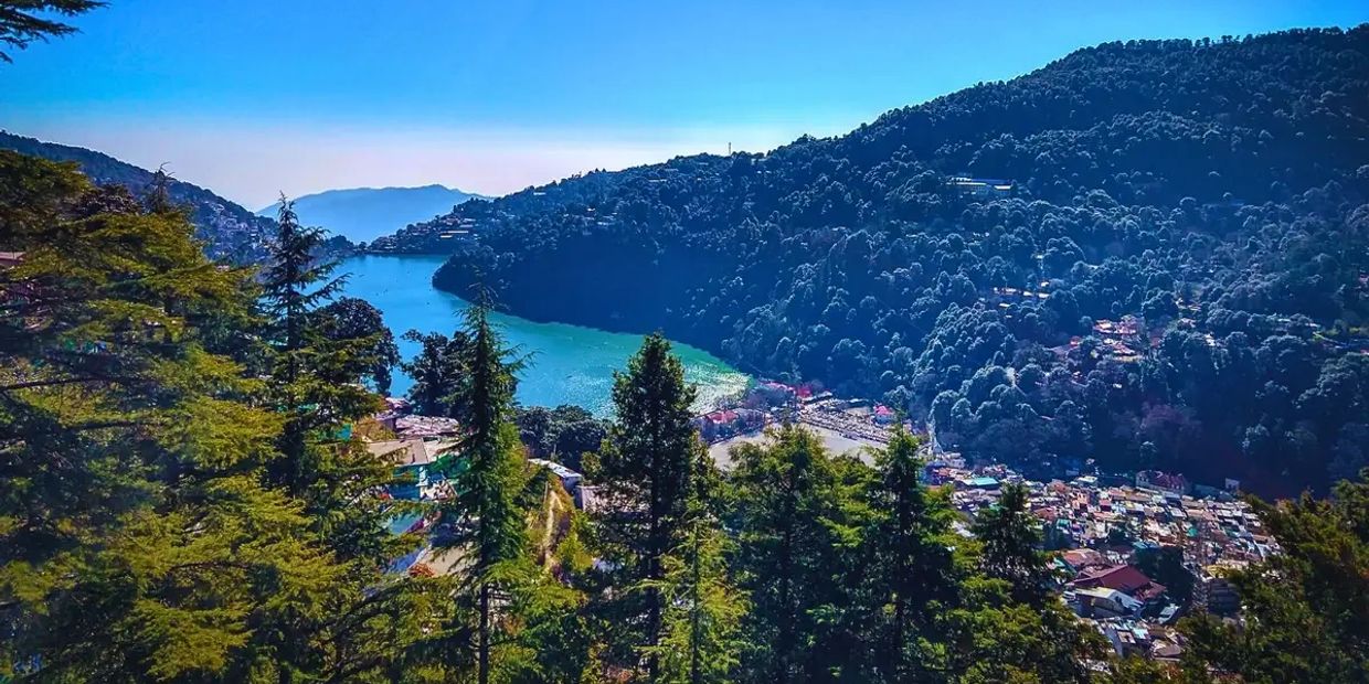 Scenic lake nestled among forested hills under a clear blue sky.