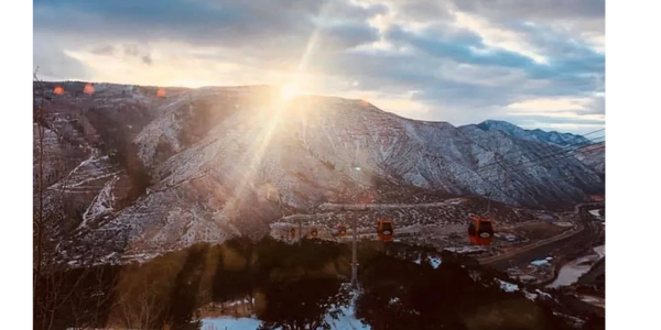 Sunset over snow-covered Colorado mountains with cable cars in the foreground.