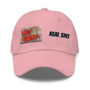 Pink cap with graffiti-style New York and bold text saying Real Shit.