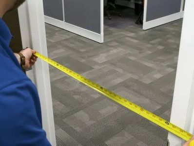 A person measuring the width of an interior doorway with a measuring tape.