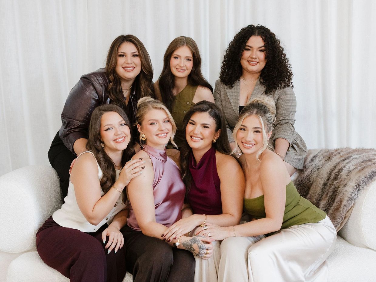 Group of seven women posing together on a couch.