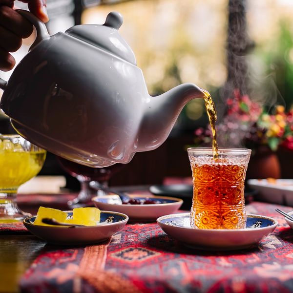 a Pot pouring our Persian Blends Black Tea from Lahijan into a glass for drinking