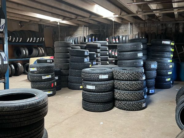 Stacks of tires neatly arranged in a warehouse with concrete walls and ceiling.