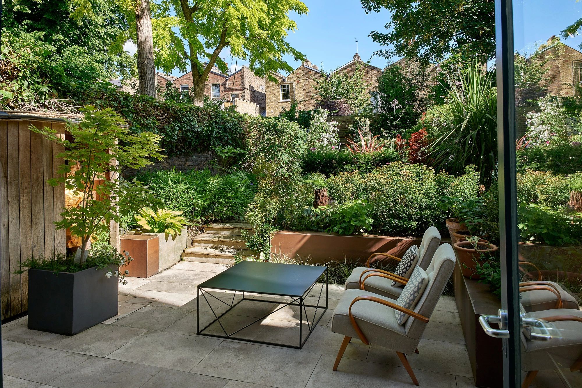 Garden terrace with low chairs and steps and porcelain cladding
