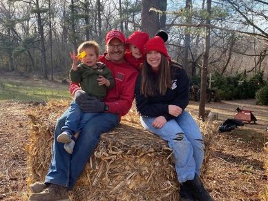 Family sitting on a hay bale outdoors in fall.