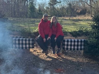 Couple sitting on a plaid blanket-covered bench outdoors.