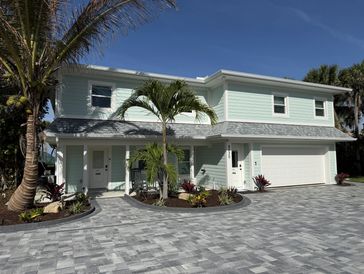 Modern two-story house with mint green exterior and palm trees.
