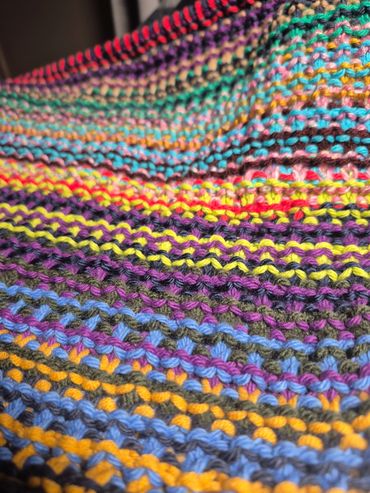 Close-up of a colorful knitted fabric with vibrant yarn stripes.