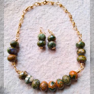 Handmade necklace and earrings with green and orange beads on gold wire.