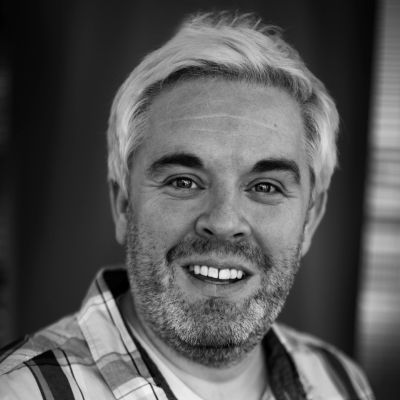 Black and white portrait of a smiling man with a beard.