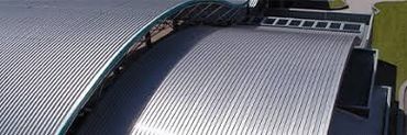 Curved metal roof structure with corrugated panels under clear daylight.